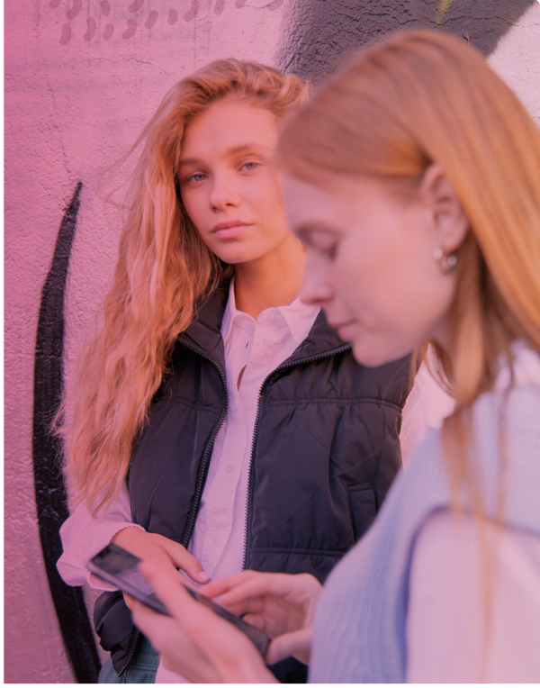 Deux étudiants internationaux collaborant sur un appareil mobile en extérieur
